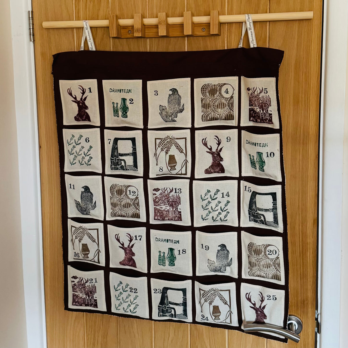 A a decorative fabric advent calendar with Scottish-themed designs hanging on a door.